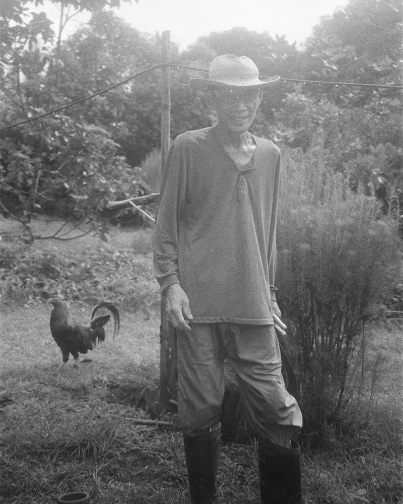 A black and white photograph of a man with a rooster